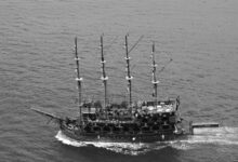 Aerial black and white photo of a pirate ship sailing the ocean, showcasing nautical adventure.