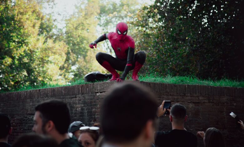 Spider-Man cosplayer posing for photos at an outdoor event, attracting a lively crowd.