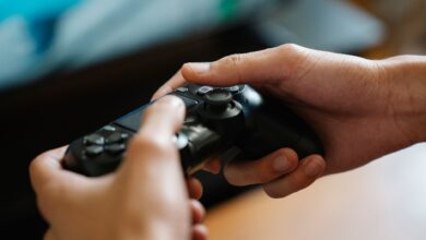 Crop unrecognizable man with modern gamepad playing video game while having free time at home