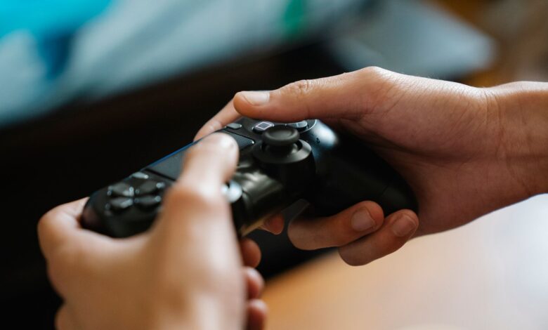 Crop unrecognizable man with modern gamepad playing video game while having free time at home
