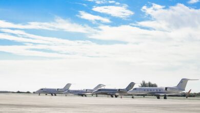 Row of private jets parked on a clear day at an open runway, showcasing aviation and luxury travel.