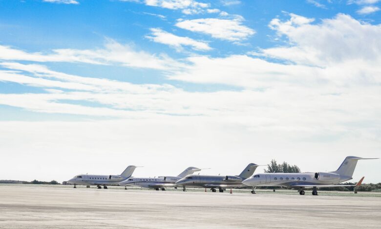 Row of private jets parked on a clear day at an open runway, showcasing aviation and luxury travel.