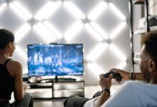 Two adults are having fun playing video games in a stylish, modern living room with LED lighting.