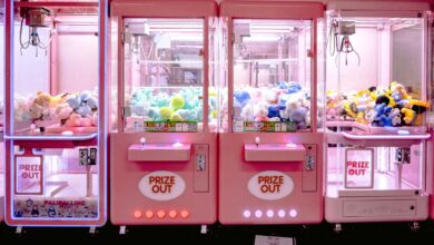 Rows of illuminated pink claw machines filled with vibrant soft toys indoors.