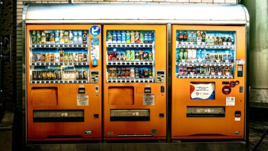 Eye-catching orange vending machines offer a variety of drinks indoors, illuminated brightly.