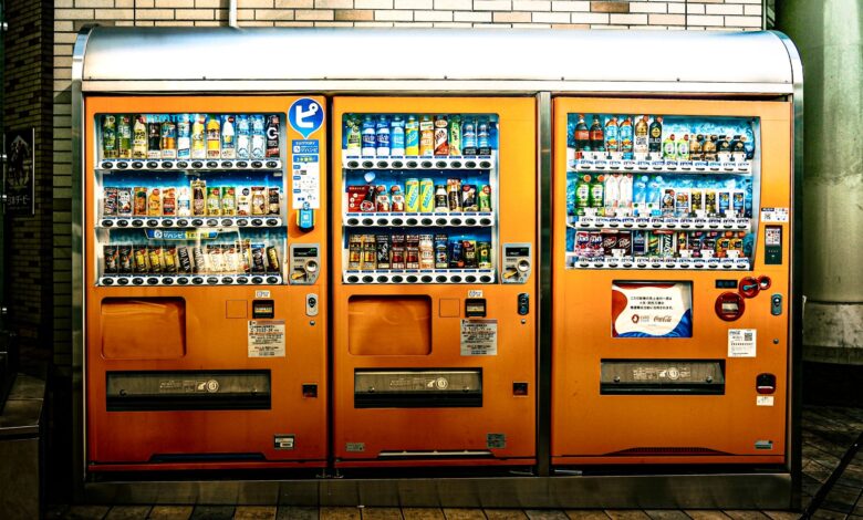 Eye-catching orange vending machines offer a variety of drinks indoors, illuminated brightly.