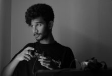A man deeply focused while playing a video game using a game controller, captured in monochrome.