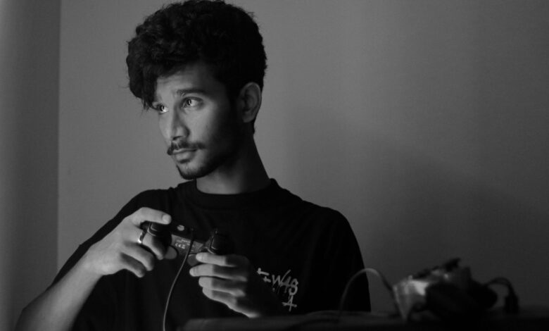 A man deeply focused while playing a video game using a game controller, captured in monochrome.