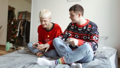 Two men in festive sweaters playing video games and enjoying each other's company at home.