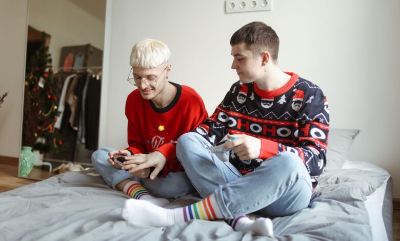 Two men in festive sweaters playing video games and enjoying each other's company at home.