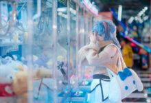 Cosplayer in vibrant outfit plays a claw machine in a colorful arcade setting in Vietnam.