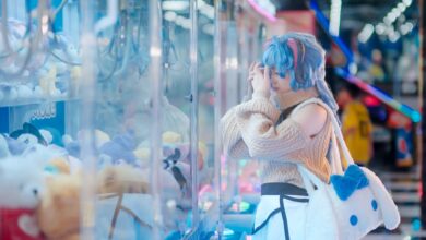 Cosplayer in vibrant outfit plays a claw machine in a colorful arcade setting in Vietnam.