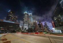 Vibrant night view of downtown Los Angeles with illuminated skyscrapers and light trails.
