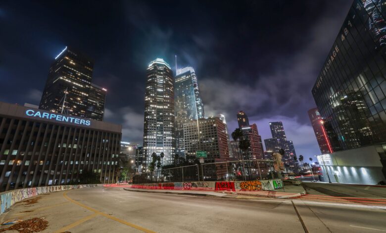 Vibrant night view of downtown Los Angeles with illuminated skyscrapers and light trails.