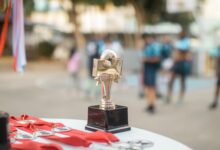 Close-up of a polished soccer trophy with medals at an outdoor sports award ceremony.