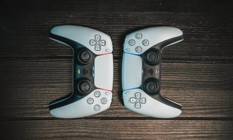 Two gaming controllers aligned symmetrically on a dark wooden surface, top view.