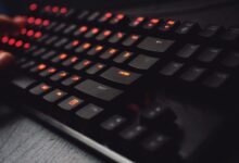 Detailed view of a gaming keyboard with backlit keys and glowing red lights.