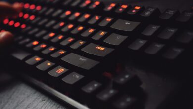 Detailed view of a gaming keyboard with backlit keys and glowing red lights.