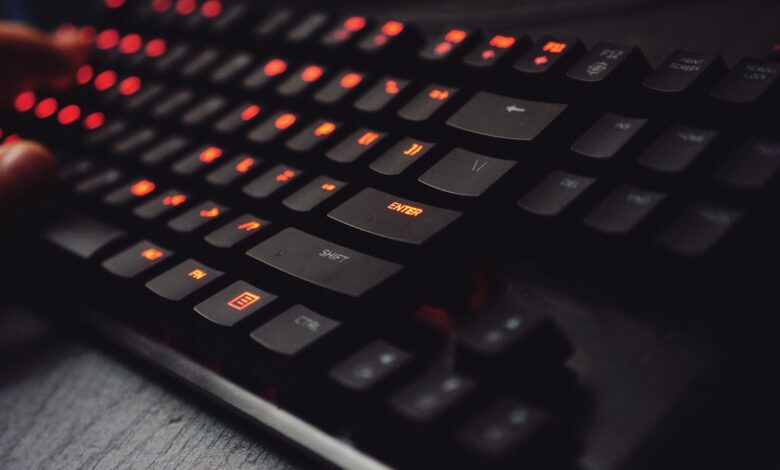Detailed view of a gaming keyboard with backlit keys and glowing red lights.