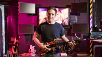 Adult male playing guitar controller in a vibrant gaming setup indoors, showcasing esports and recreation.