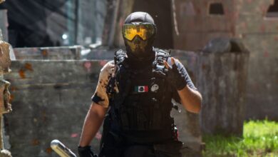 Armed paintball player with helmet and tactical gear in dynamic outdoor setting.