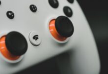 Detailed close-up of a modern white gaming controller featuring vibrant orange buttons.