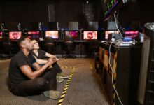Two diverse men focused on gaming in a modern arcade setting, showcasing technology and camaraderie.