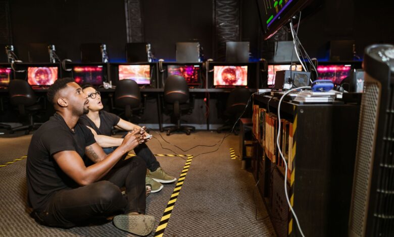 Two diverse men focused on gaming in a modern arcade setting, showcasing technology and camaraderie.