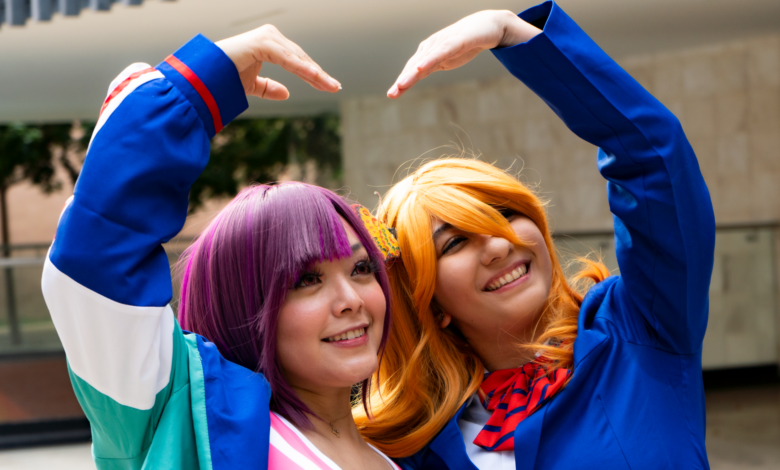 Smiling cosplayers in colorful costumes pose with a heart gesture, expressing friendship and joy.