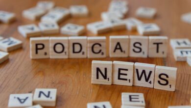 Wooden letter tiles spelling out 'PODCAST NEWS' on a wooden surface.