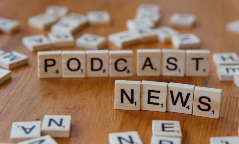 Wooden letter tiles spelling out 'PODCAST NEWS' on a wooden surface.