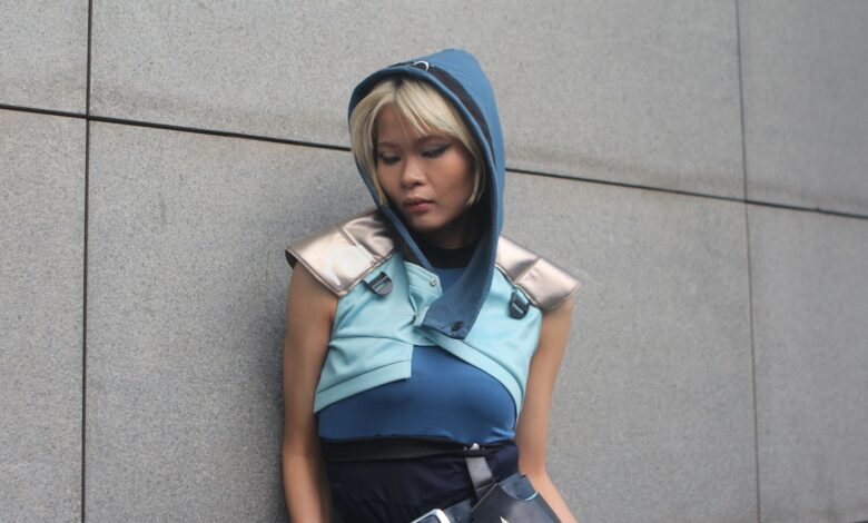 Person in a blue fantasy costume against a concrete wall.