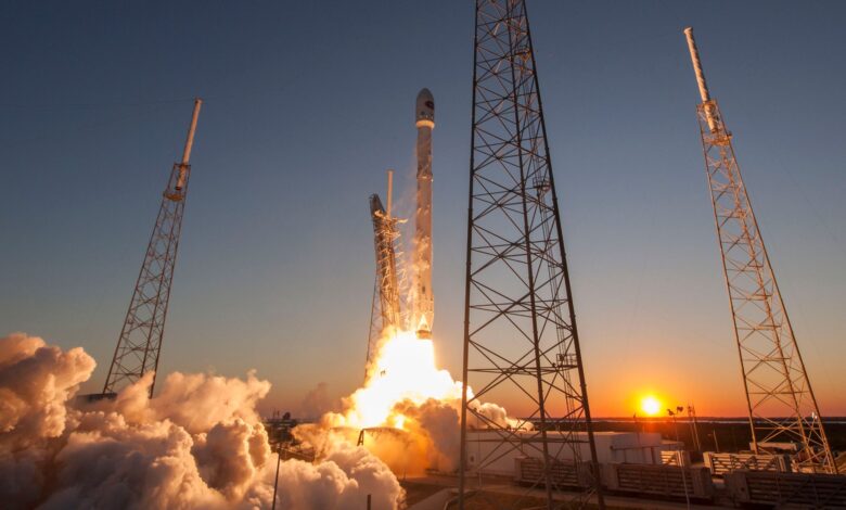 Low angle of modern rocket taking off into cloudless sky during beautiful sunset over space factory