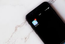 Close-up of an iPhone showing a notification on the App Store icon against a marble background.