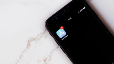 Close-up of an iPhone showing a notification on the App Store icon against a marble background.