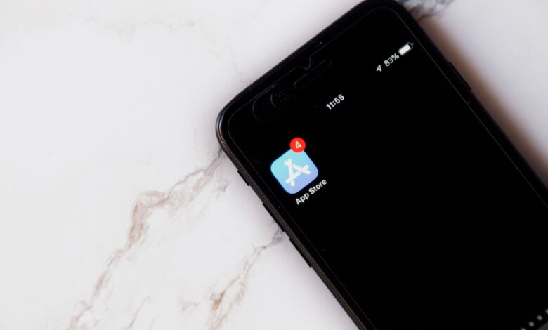 Close-up of an iPhone showing a notification on the App Store icon against a marble background.