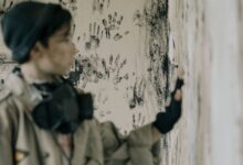 Blurred person in abandoned building with handprints on wall conveys eerie atmosphere.