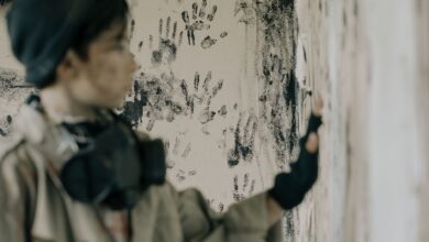 Blurred person in abandoned building with handprints on wall conveys eerie atmosphere.