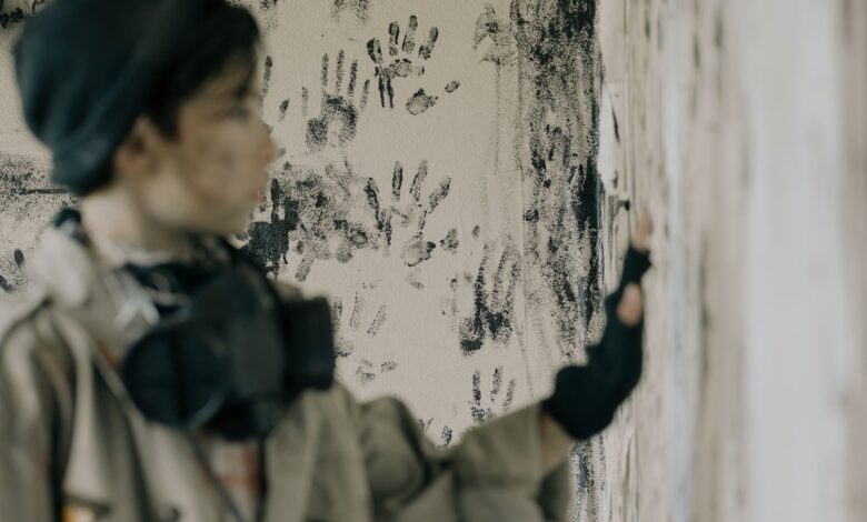 Blurred person in abandoned building with handprints on wall conveys eerie atmosphere.