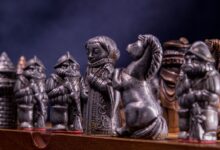 Close-up of metallic medieval chess pieces on a board, capturing the craftsmanship and detail.
