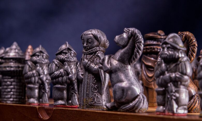 Close-up of metallic medieval chess pieces on a board, capturing the craftsmanship and detail.