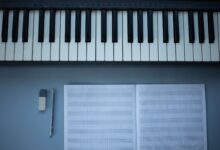 Flat lay of piano keys, sheet music, pencil, and eraser for music composition.