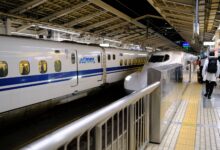 Shinkansen bullet train at a busy Tokyo station platform with passengers boarding.