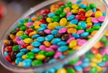 A glass bowl filled with colorful candy-coated chocolates, perfect for a festive party setting.