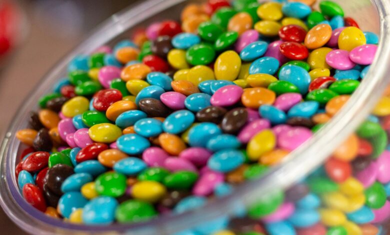 A glass bowl filled with colorful candy-coated chocolates, perfect for a festive party setting.