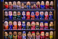 Colorful nesting dolls depicting various sports teams displayed on shelves.
