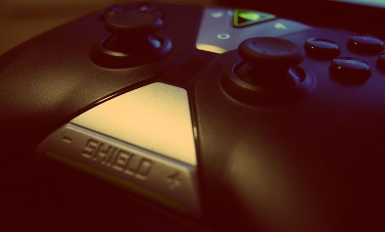Close-up view of a modern gaming controller, highlighting joystick and buttons with a 'shield' design.