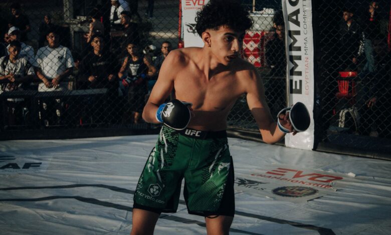 Young male fighter in action during an MMA fight in a cage.