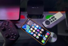 Stylish home entertainment setup featuring an iPhone, Apple TV, and gaming controller on a dark surface.