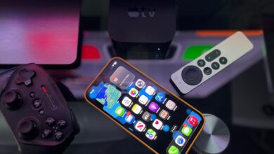 Stylish home entertainment setup featuring an iPhone, Apple TV, and gaming controller on a dark surface.